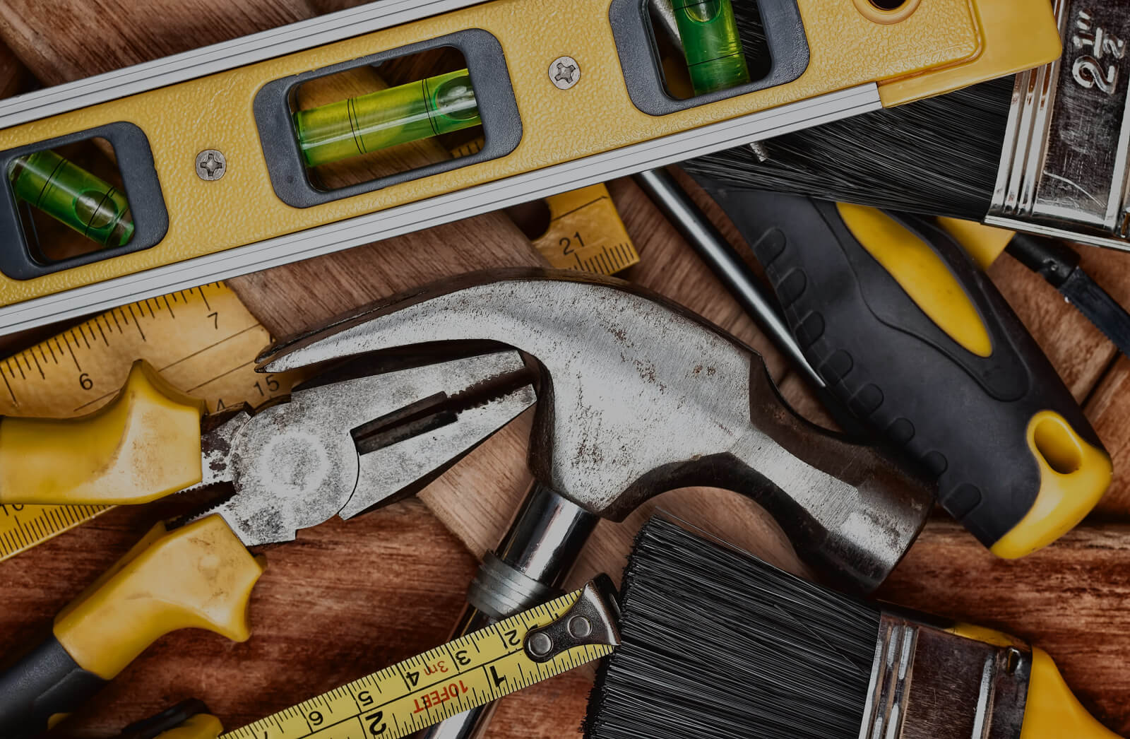 Hand tools, paintbrushes and a spirit level on a workbench